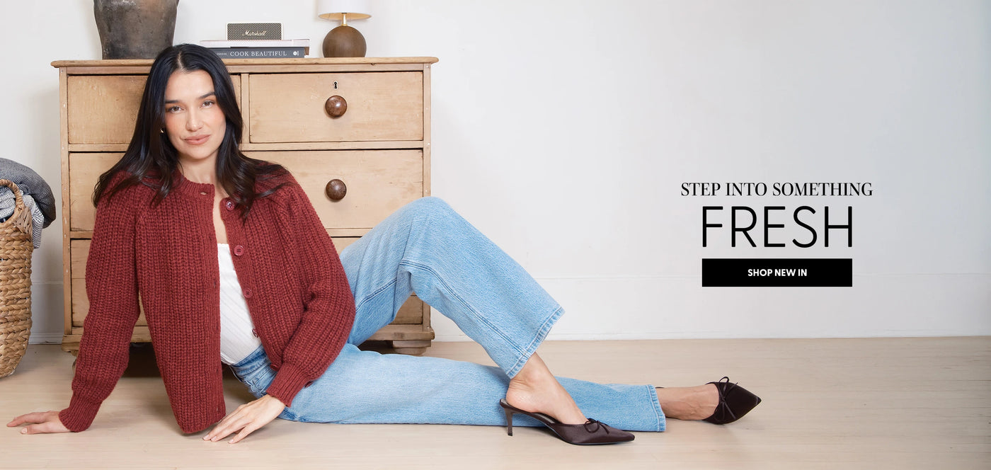 Woman sitting on the floor wearing a red cardigan and blue jeans with text 'Step into Something Fresh' on a white background.